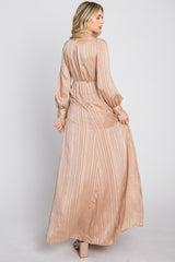 woman wearing a long beige striped maxi dress with balloon sleeves and open back, shown from the back