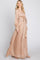 woman wearing a blush long sleeve pleated maxi dress with a tie waist detail and a flowing silhouette