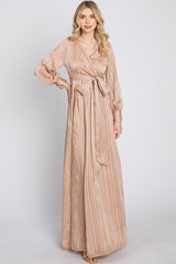 woman wearing a champagne-colored striped maxi dress with a tie waist and long sleeves