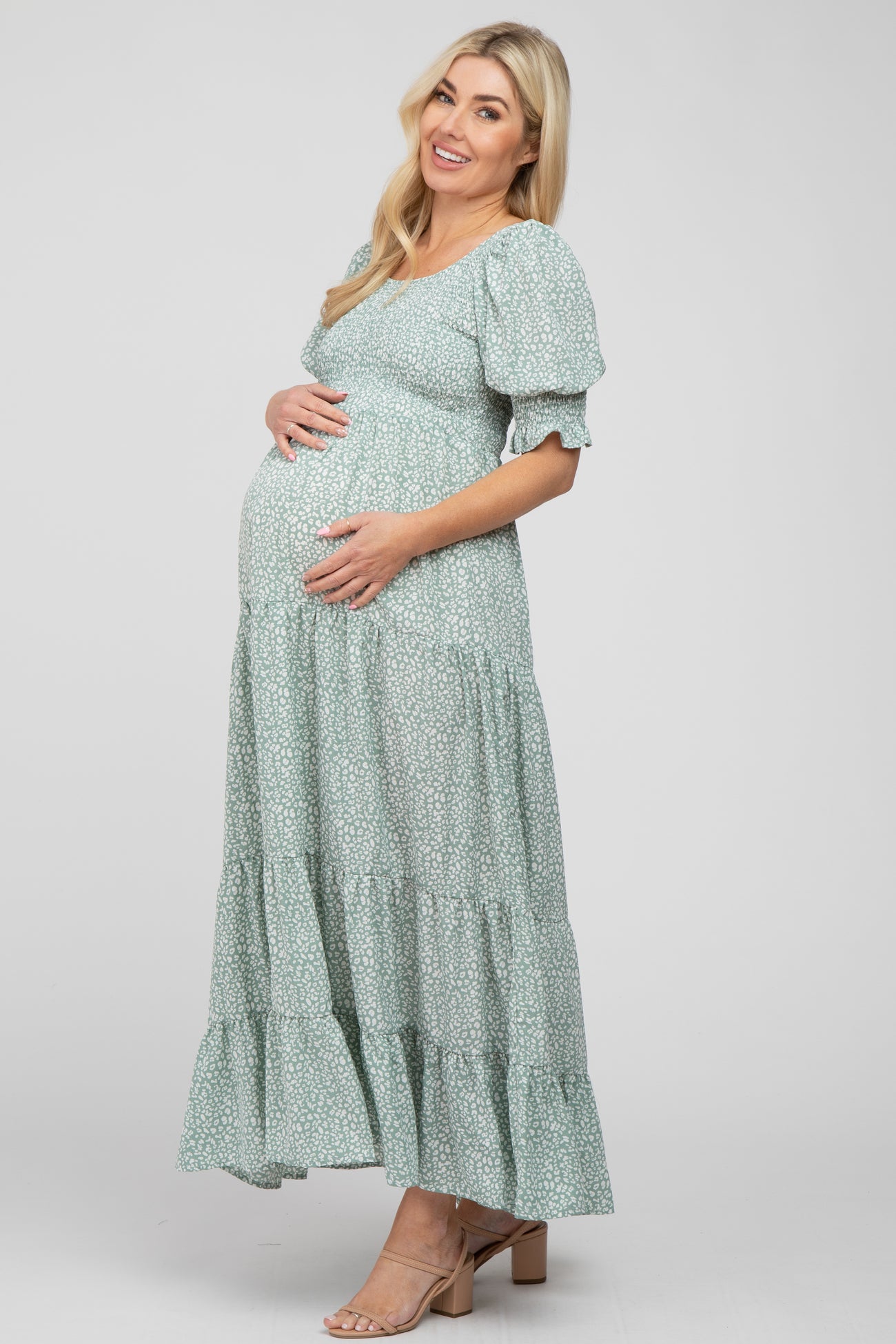 Pregnant woman wearing a light green floral smocked maternity maxi dress with puff sleeves