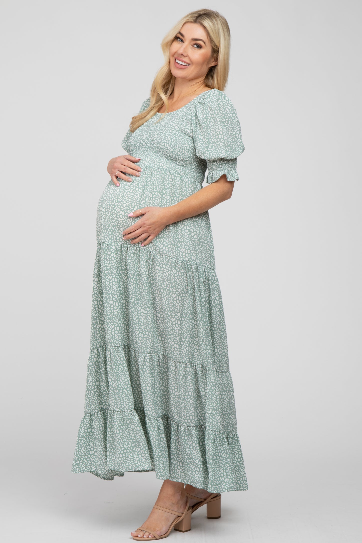 Pregnant woman wearing a light green floral smocked maternity maxi dress with puff sleeves
