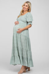 Pregnant woman wearing a light green floral smocked maternity maxi dress with puff sleeves