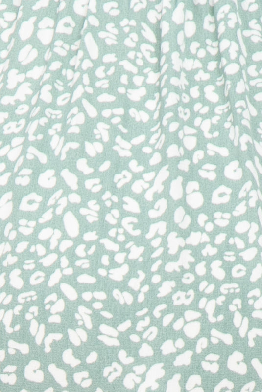 Close up of sage green fabric with white leopard print pattern