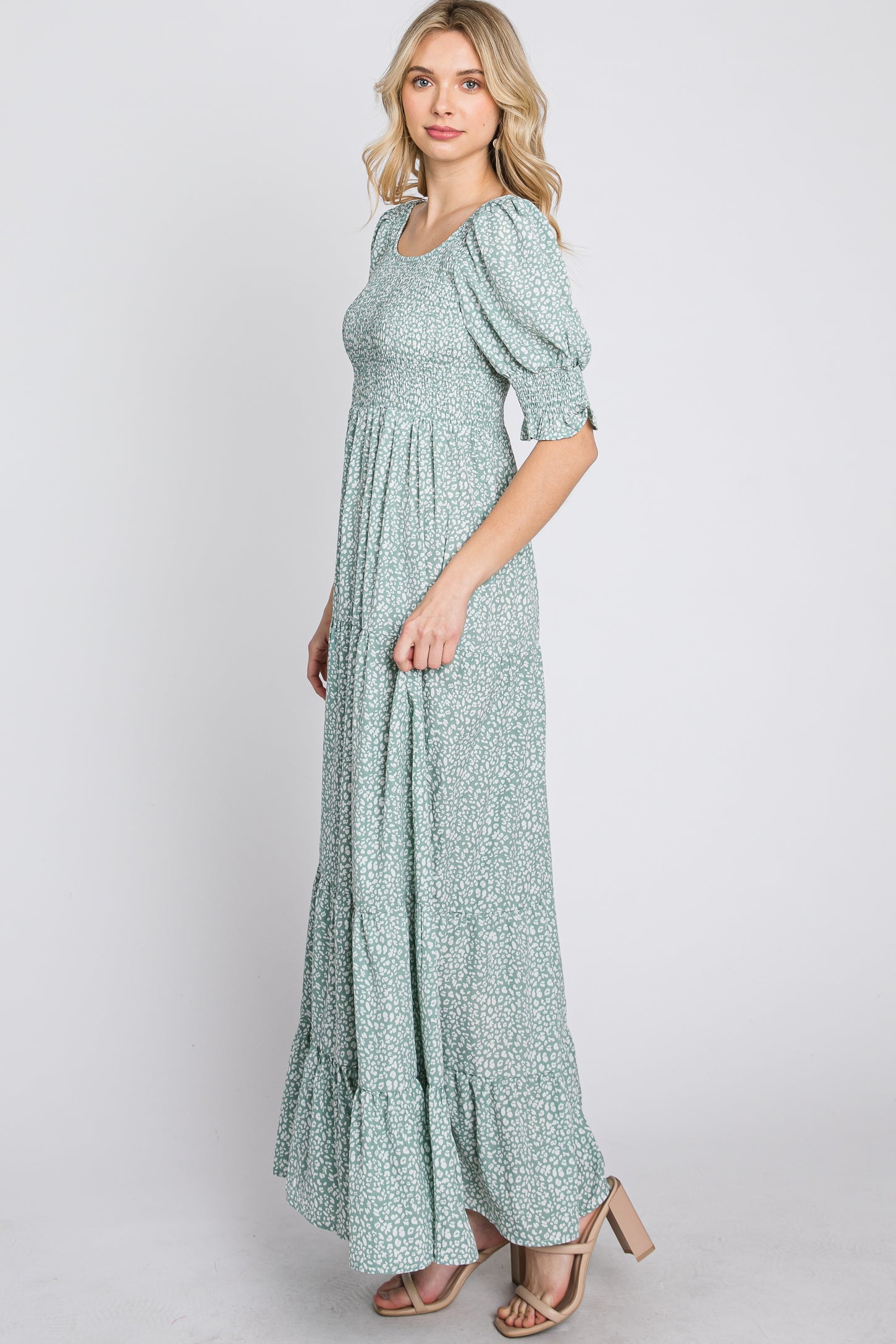 woman wearing a sage green floral smocked maxi dress with puff sleeves and tiered skirt