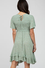 Back view of woman wearing sage green floral mini dress with smocked bodice and ruffle hem