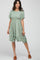woman wearing a sage green floral smocked maternity dress with ruffle hem and brown slide sandals