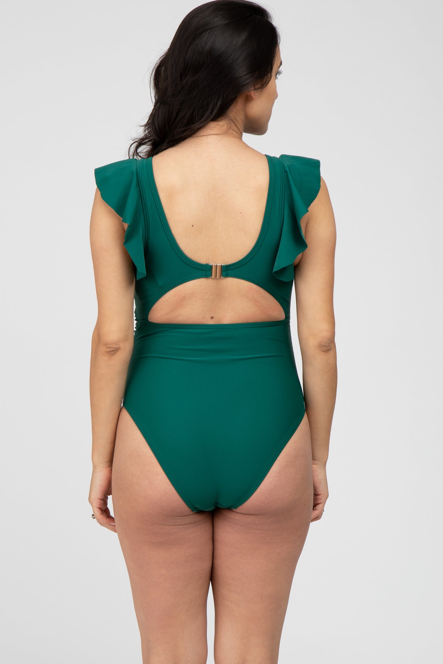 Back view of a woman wearing a dark green one-piece swimsuit with ruffle sleeves and a cutout back design