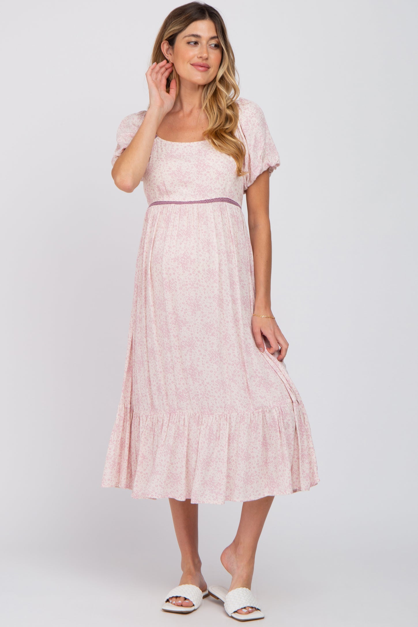 woman wearing a light pink floral maternity midi dress with puff sleeves and a ruffled hem