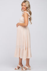 pregnant woman in cream smocked maternity midi dress with ruffle sleeves and block heel sandals
