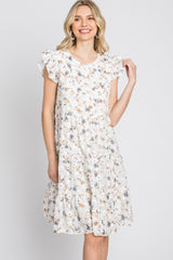 Blonde woman wearing a white tiered floral mini dress with ruffle sleeves against a white background