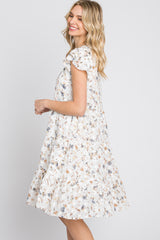 smiling woman wearing a white floral tiered babydoll dress with ruffle sleeves against a white background