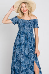smiling woman in blue floral off-the-shoulder maxi dress and straw hat