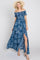 woman wearing a blue floral off-the-shoulder maxi dress with a side slit and straw sun hat