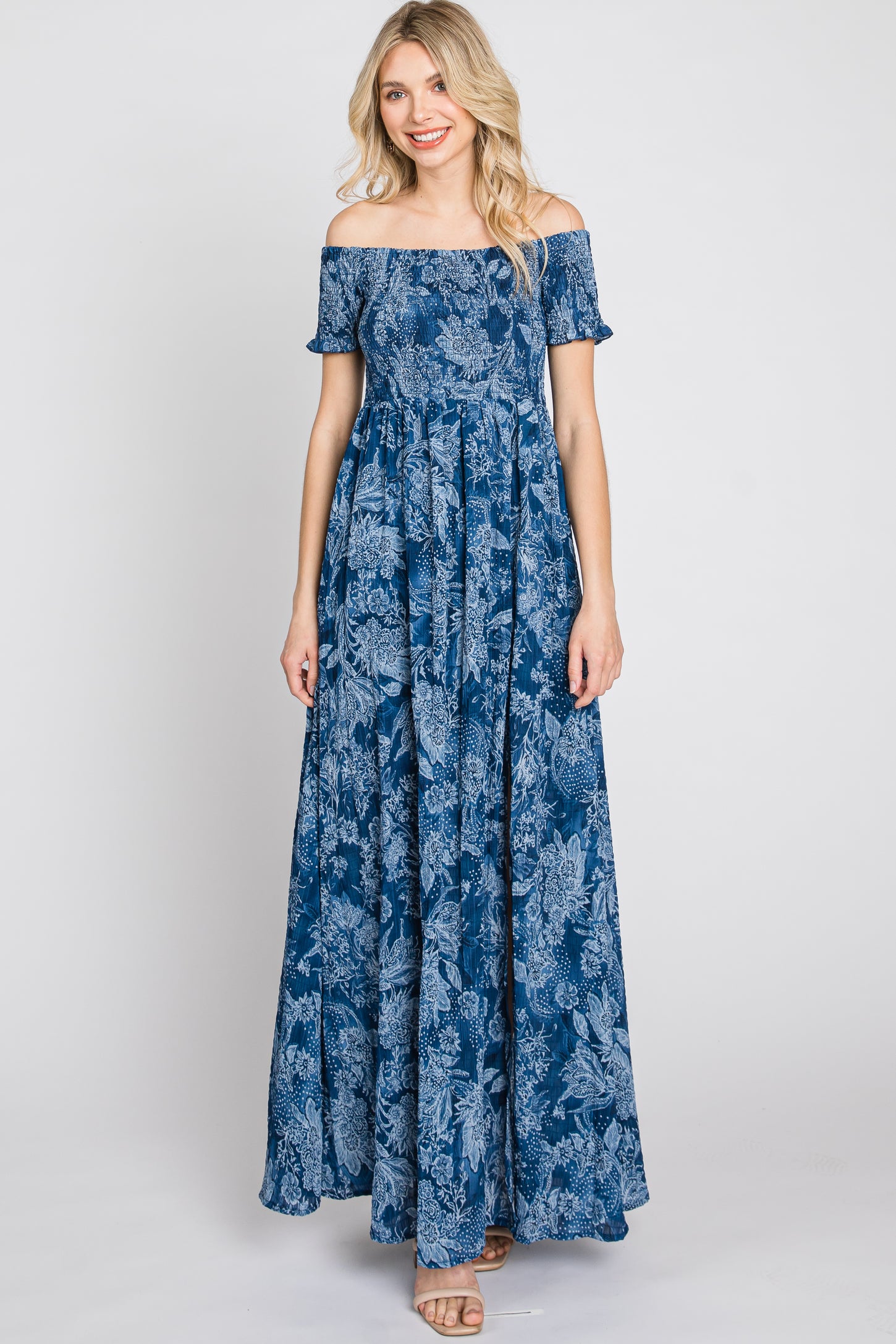 Woman wearing a blue off-the-shoulder floral maxi dress with a smocked bodice and short sleeves