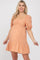 pregnant woman wearing a peach puff sleeve maternity mini dress with a ruffled hem