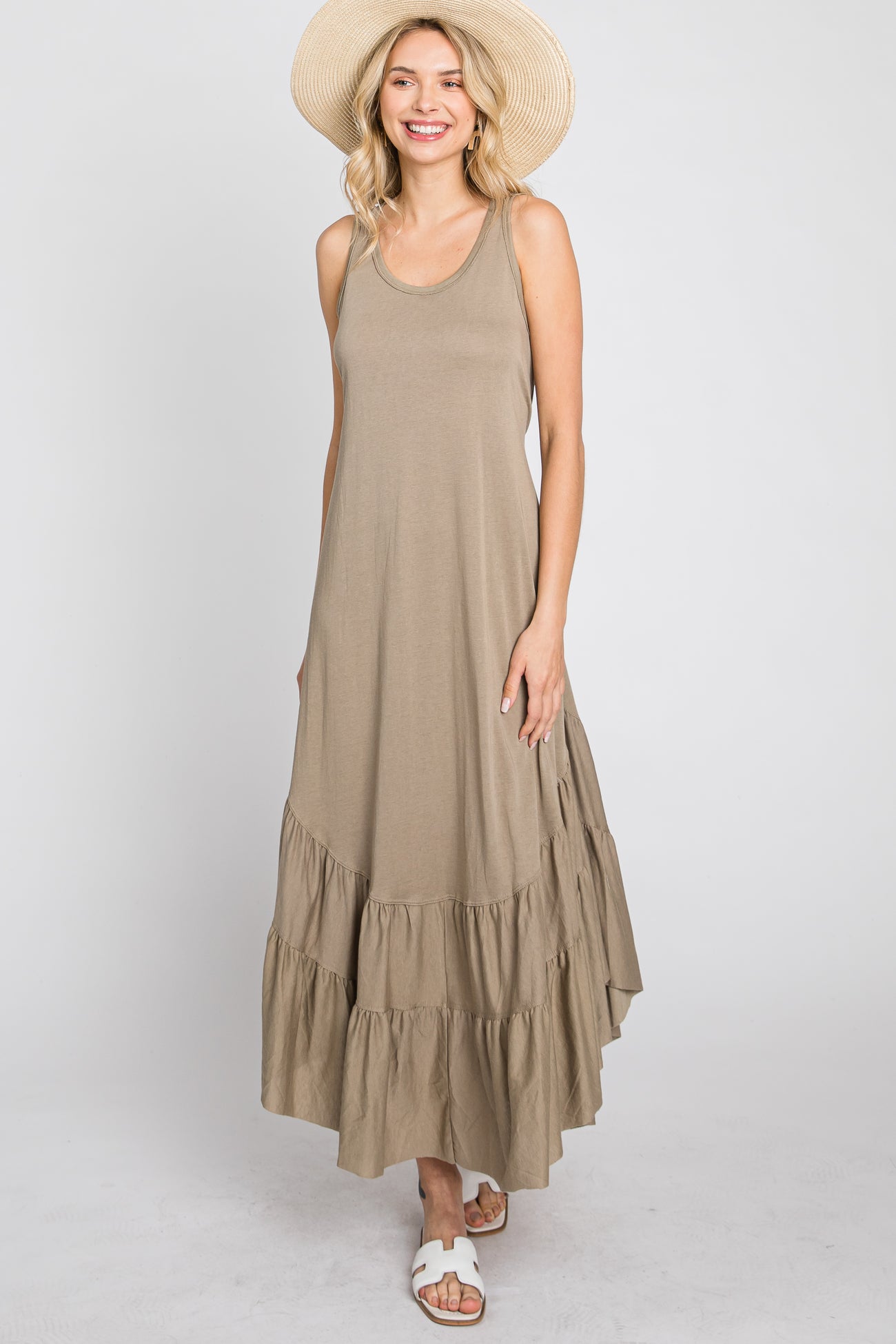 woman wearing a taupe sleeveless tiered maxi dress and straw sun hat against a white background