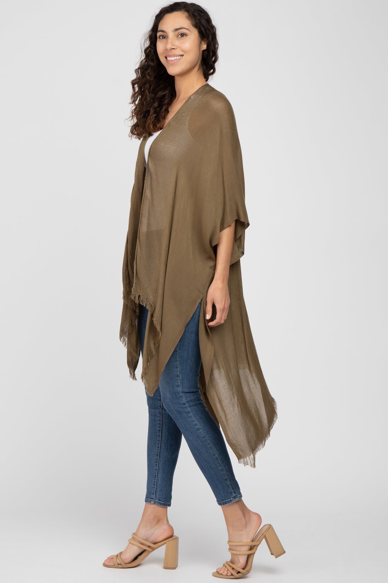 woman wearing olive green lightweight knit kimono with fringe hem and blue skinny jeans