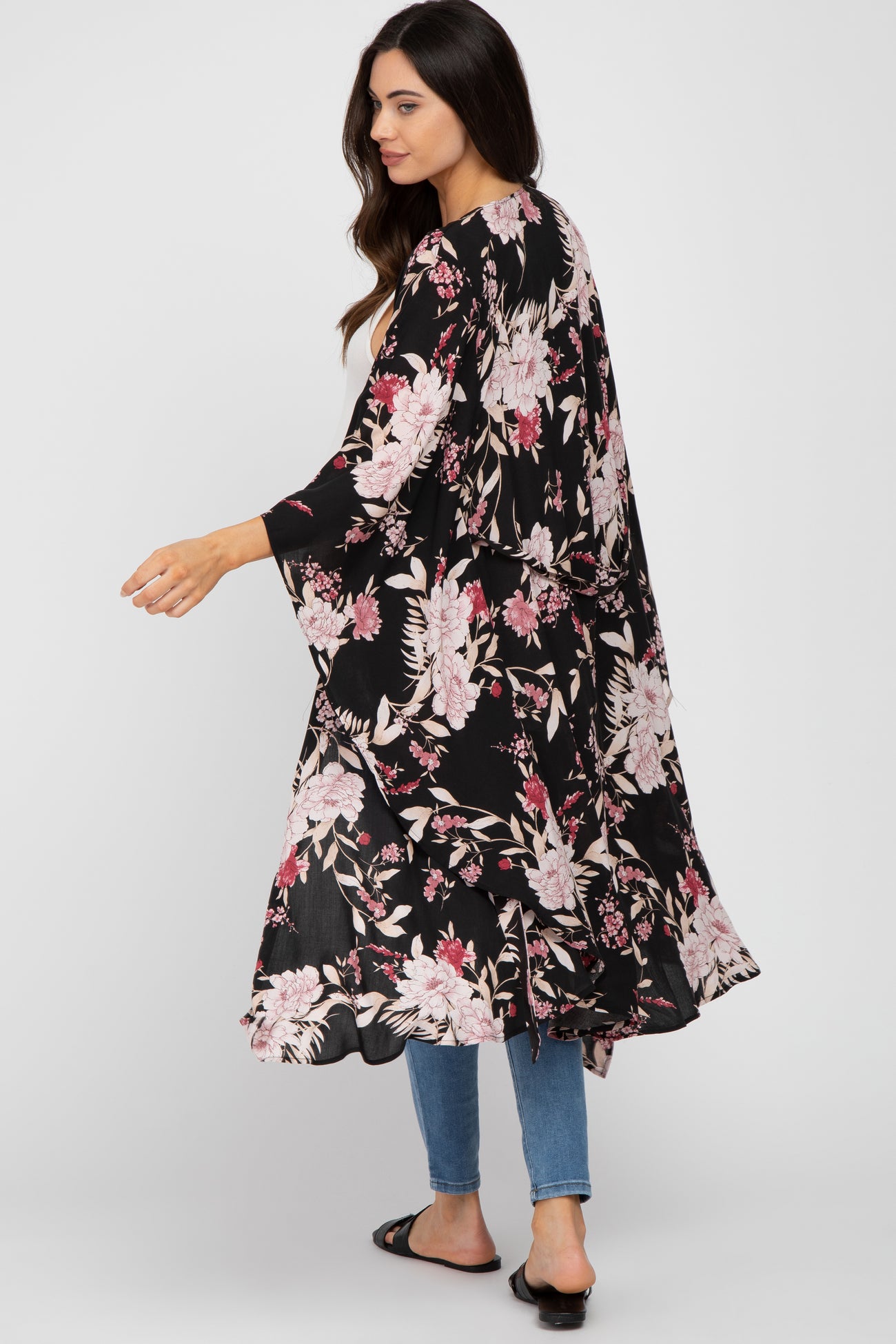 Woman wearing a long black floral print kimono over a white top and blue jeans