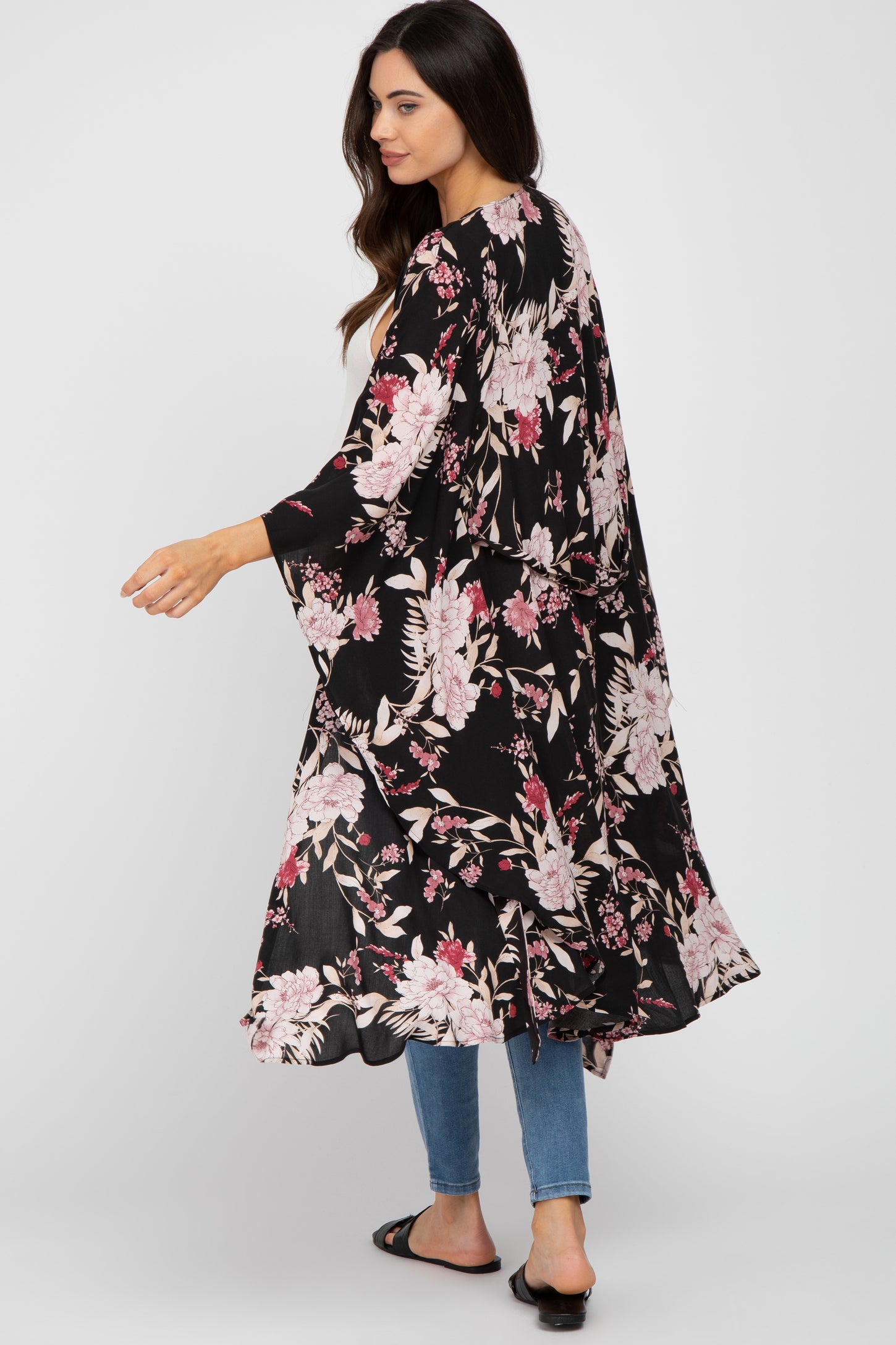 Woman wearing a long black floral print kimono over a white top and blue jeans