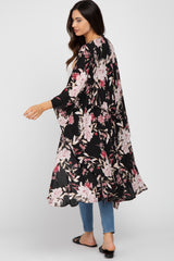 Woman wearing a long black floral print kimono over a white top and blue jeans