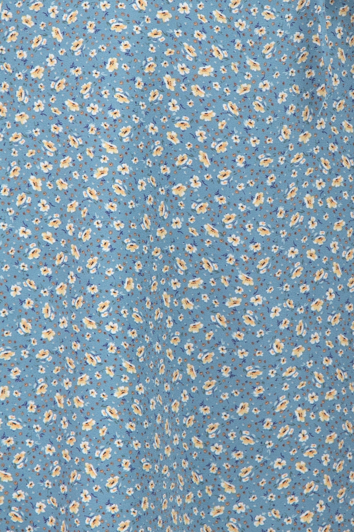 Close up of blue fabric with a small yellow and white floral ditsy print pattern