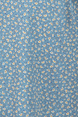 Close up of blue fabric with a small yellow and white floral ditsy print pattern