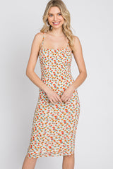 woman wearing a white midi dress with orange floral print and spaghetti straps