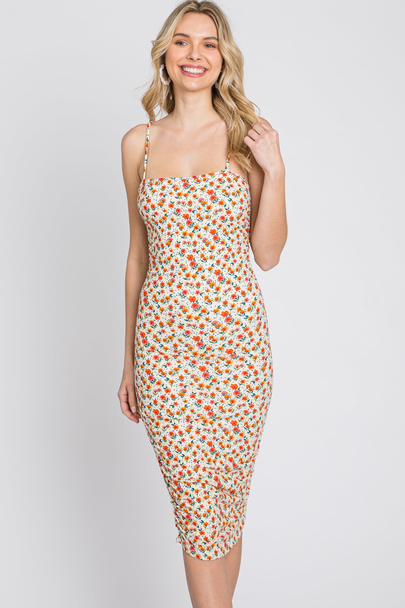 woman wearing a white midi dress with orange and yellow floral print and spaghetti straps