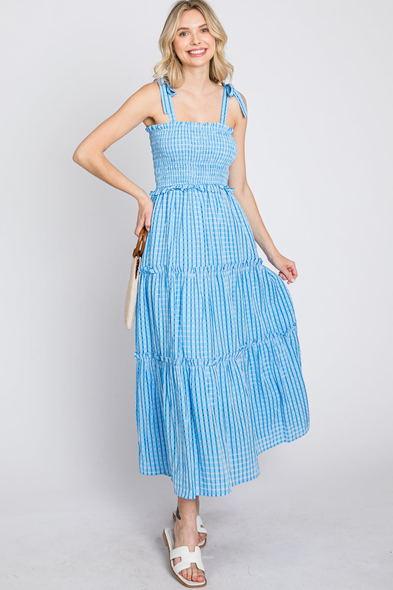 woman wearing a blue and white gingham tiered midi dress with tie straps and smocked bodice