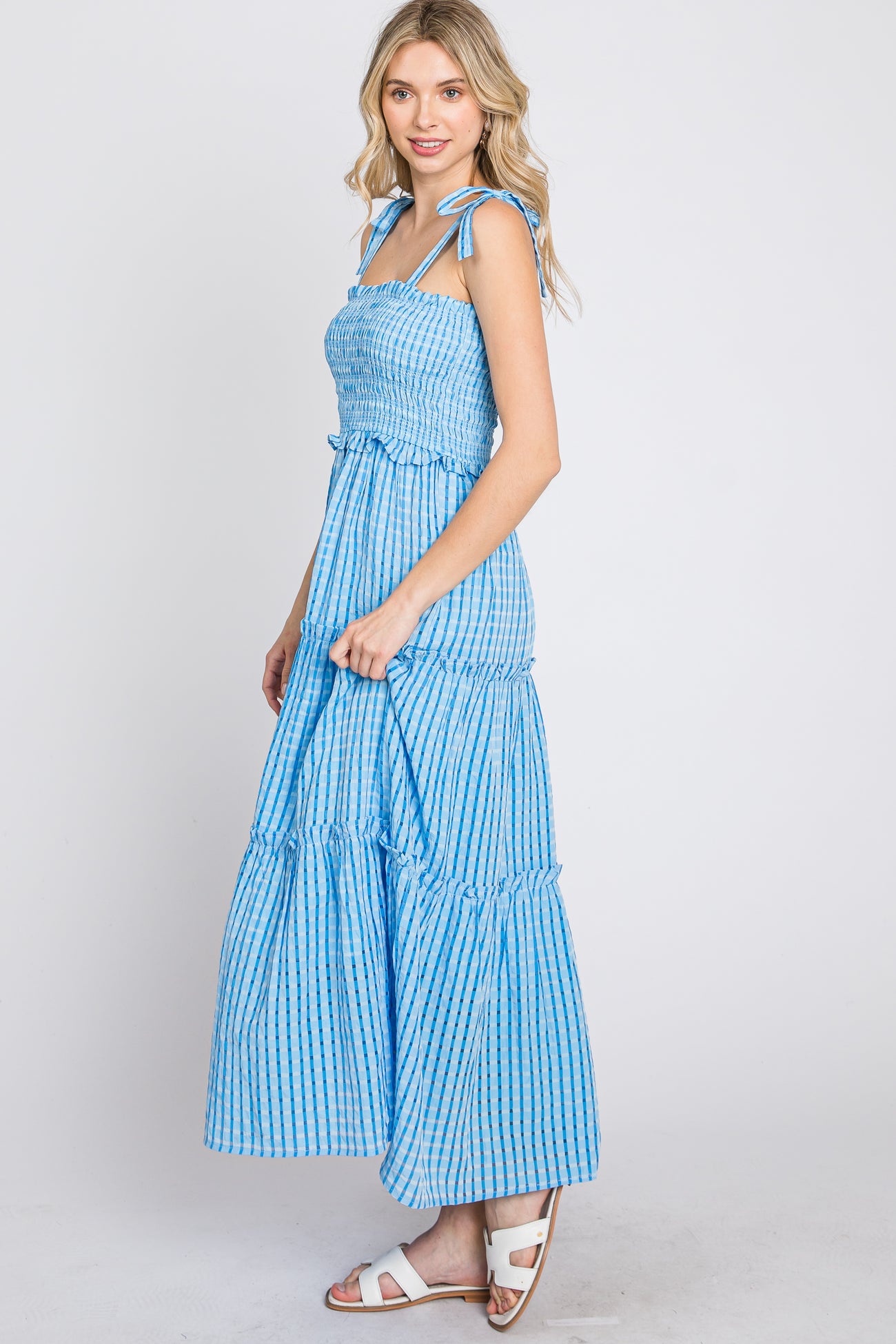 woman wearing a blue and white gingham tiered maxi dress with tie straps and smocked bodice