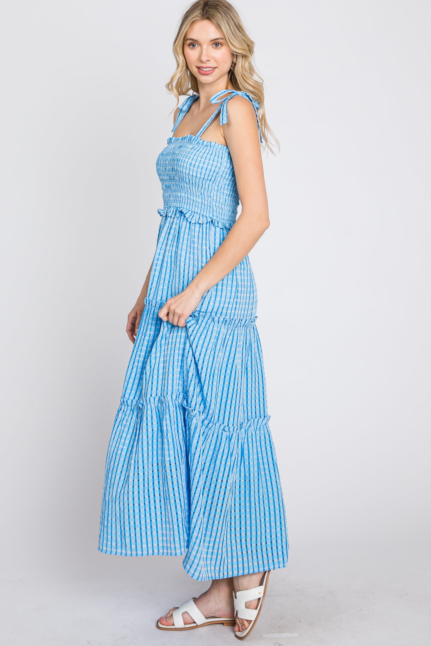 woman wearing a blue and white gingham tiered maxi dress with tie straps and smocked bodice