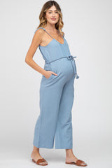 pregnant woman wearing light blue maternity jumpsuit with rope belt and brown sandals