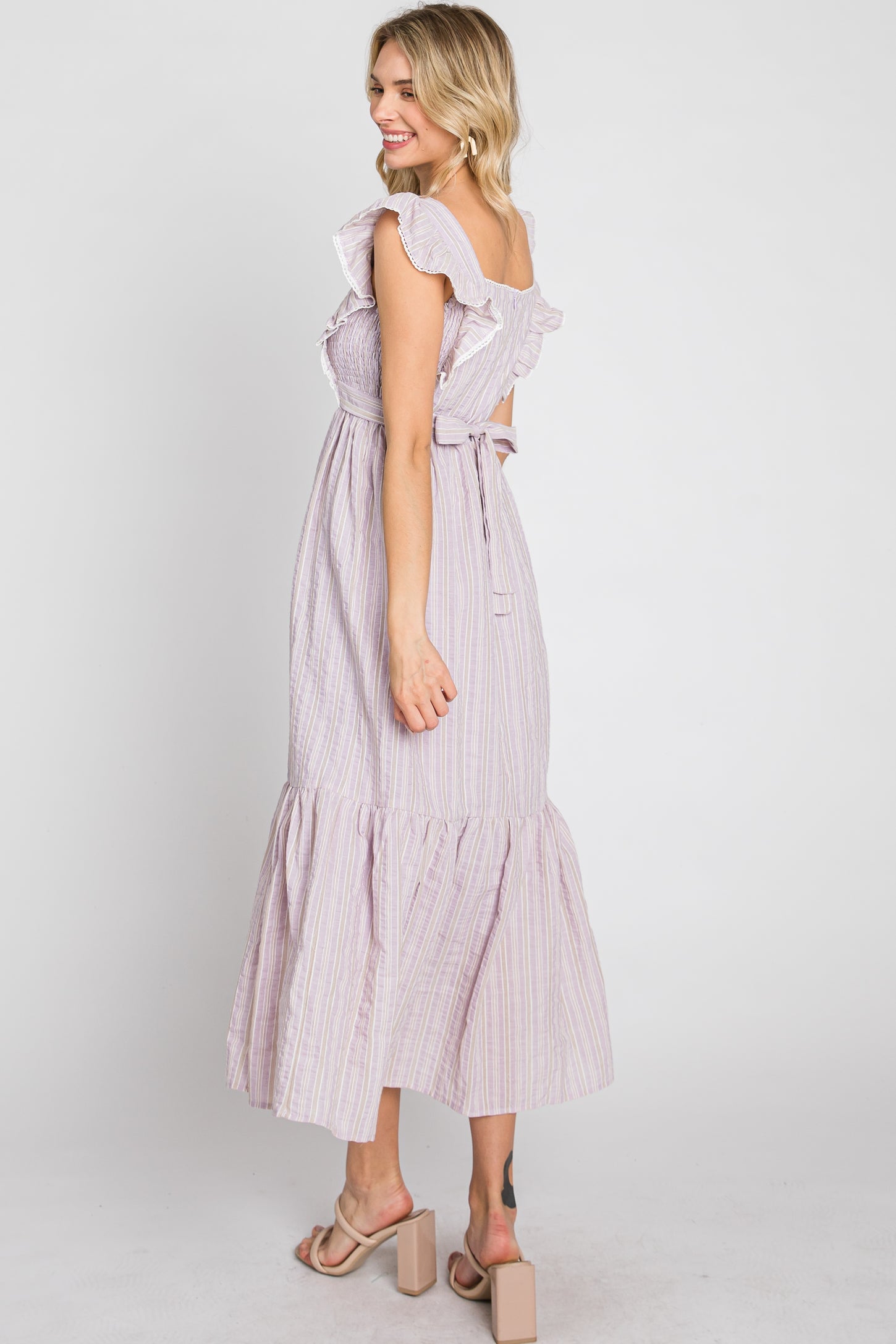 woman wearing a lavender striped midi dress with ruffle sleeves and a tiered skirt