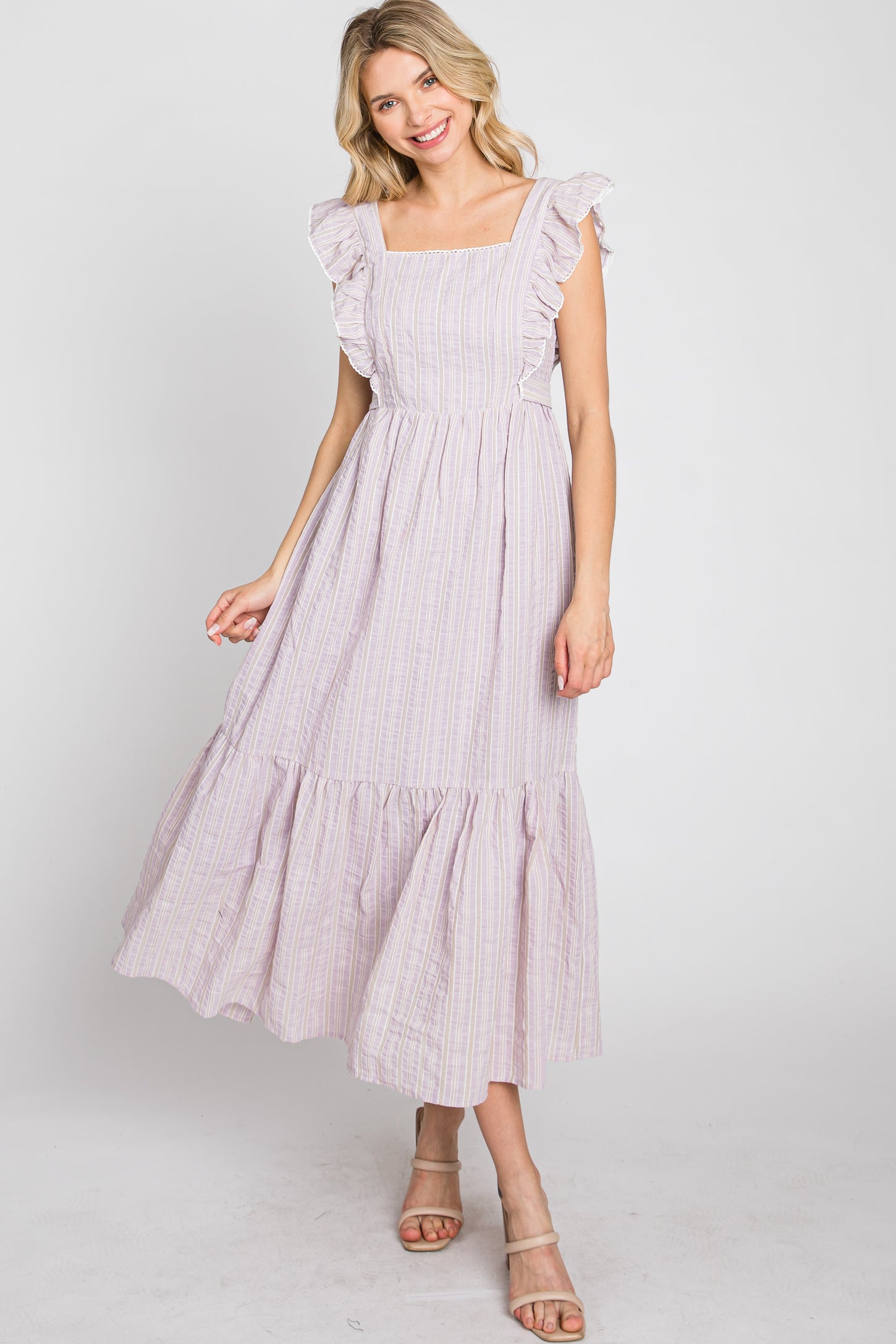 woman wearing a lavender striped midi dress with ruffle sleeves and a tiered skirt