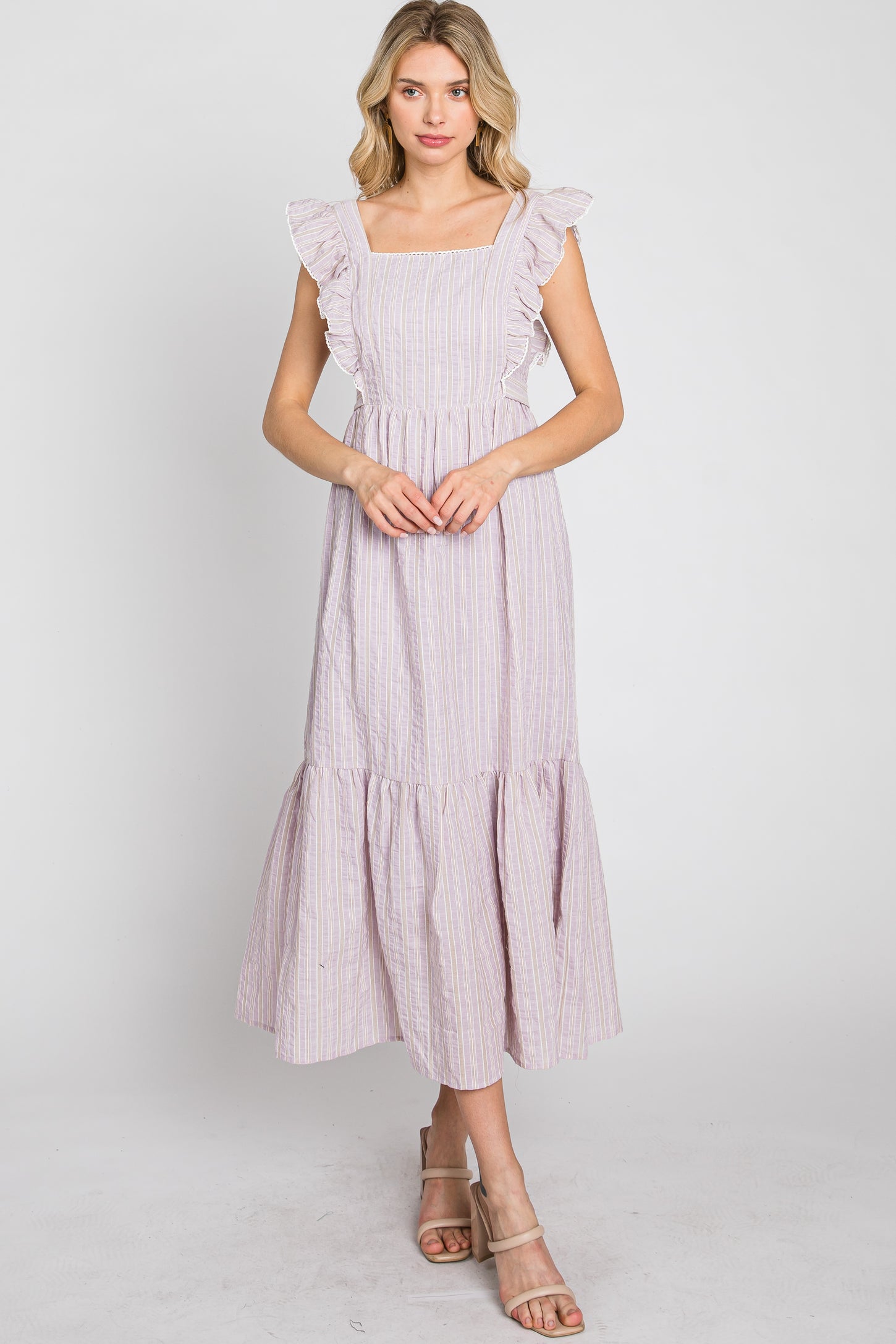 Woman wearing a lavender striped midi dress with ruffle sleeves and a tiered skirt