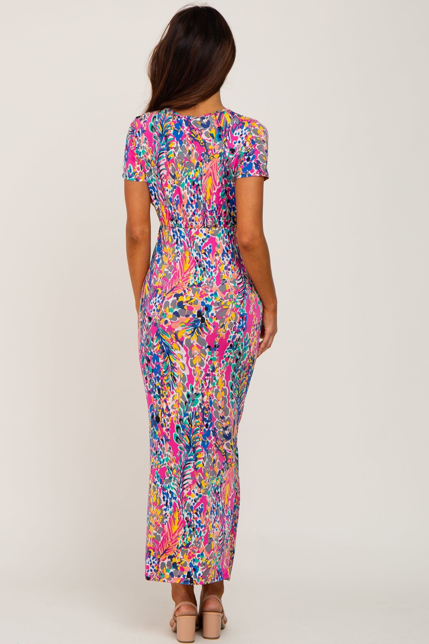back view of woman wearing colorful pink floral print short sleeve maxi dress with tan block heels