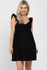 blonde woman wearing a black sleeveless maternity dress with ruffle straps and a sweetheart neckline