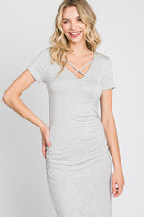 Woman wearing a grey short sleeve t-shirt dress with a crisscross v-neckline and ruched side detailing