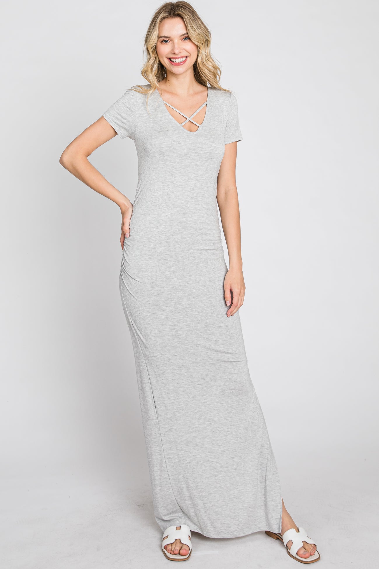 woman wearing a grey short sleeve maxi dress with a crisscross v-neckline and white sandals