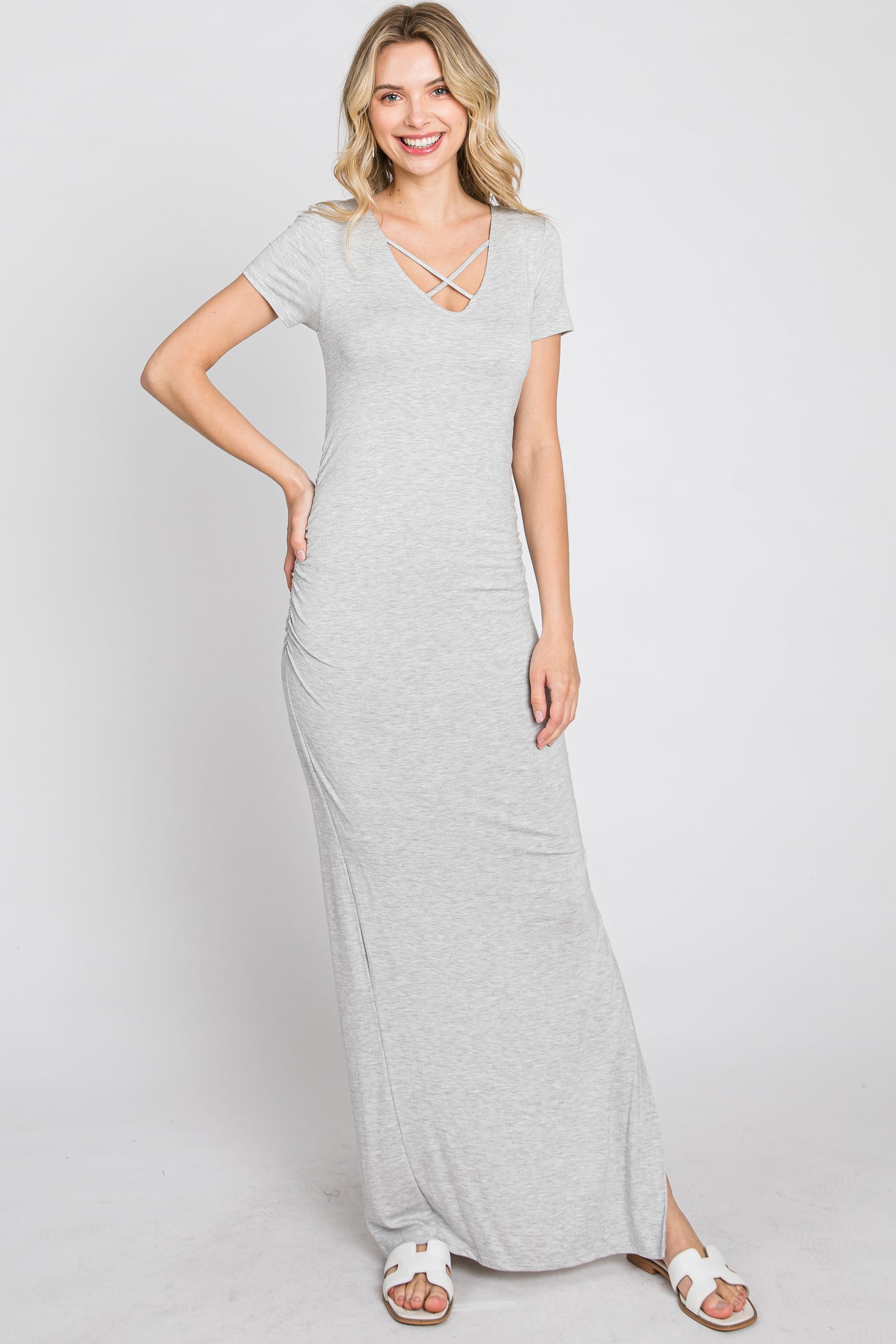 woman wearing a grey short sleeve maxi dress with a crisscross v-neckline and white sandals