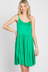 blonde woman wearing a green tiered sleeveless sundress against a white background