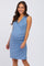 smiling pregnant woman wearing a sleeveless light blue wrap maternity dress against a white background
