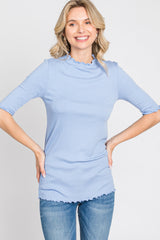 woman wearing light blue ribbed mock neck top with lettuce edge trim and denim jeans