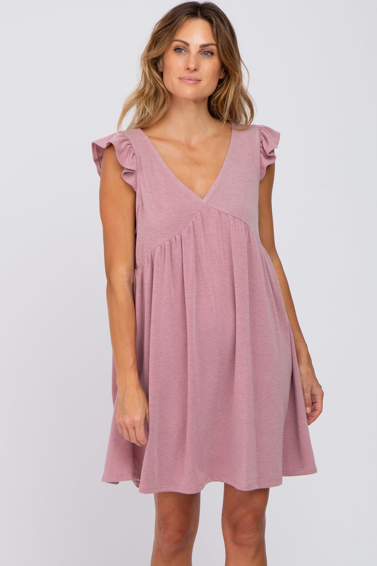 woman wearing a mauve ruffle sleeve v-neck maternity dress against a white background