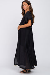 pregnant woman in a black ruffled maternity maxi dress posing against a white background