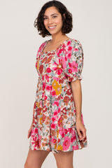 woman wearing a short sleeve tiered mini dress with a vibrant pink and orange floral pattern