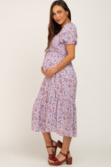 Pregnant woman in a lavender floral smocked maternity midi dress with puff sleeves and brown platform sandals