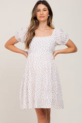 woman wearing a white floral maternity dress with puff sleeves and a square neckline