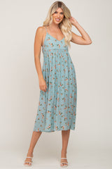 Woman wearing a light blue floral midi dress with spaghetti straps and white sandals