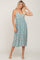 Woman wearing a light blue floral midi dress with spaghetti straps and white sandals